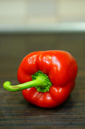 A vertical closeup shot of a Bulgarian red pepper on a wooden surfaceの写真素材