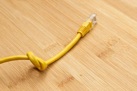 A high angle shot of a knotted yellow cable on a wooden surfaceの写真素材