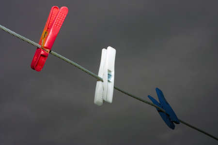 The three colorful clothespins hanging on a rope with a dark background