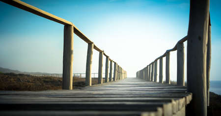 A boardwalk with wooden railings and the beautiful bright sky in the background