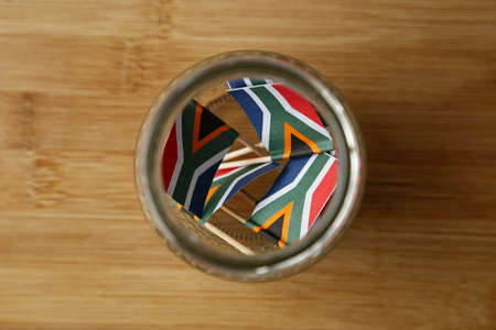 An overhead shot of small south Africa flags in a jar on a wooden surface