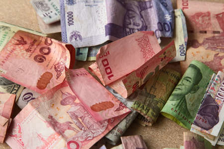 A high angle shot of a pile of banknotes from different countries on a wooden surfaceの写真素材