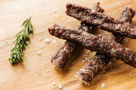 Four sticks of delicious traditional South African droewors with a rosemary seasoning on a wooden...