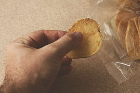 A person taking some potato chips from a plastic bagの写真素材