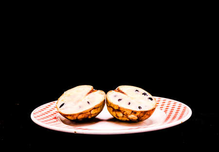 A landscape shot of a fruit laid on a plate with a pitch-black backgroundの写真素材