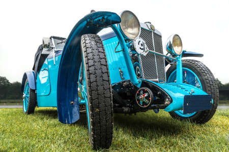 A closeup shot of a blue car with large wheels parked on a green field