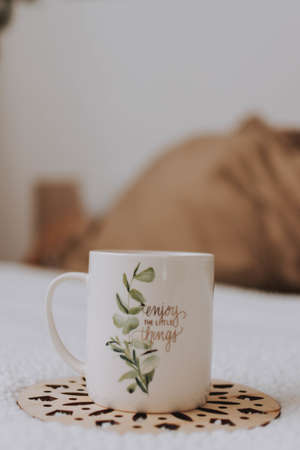 A closeup shot of a white cup with a painting put on a white table