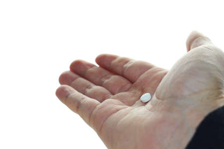 A closeup shot of a person holding a small white pill with a white backgroundの写真素材