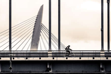 A wide angle shot of a man driving a bicycle on a bridgeの写真素材