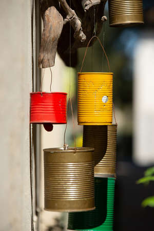 A vertical shot of panted metal cans hung in the wind outside a houseの写真素材