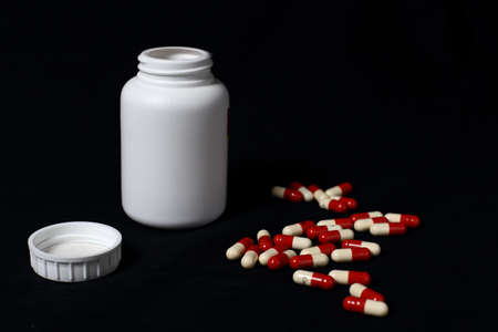 A stack of red and blue medicine capsules in front of a black backgroundの写真素材