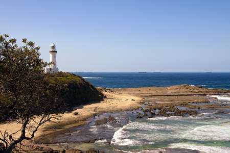 A high angle shot of a white lighthouse on the shore of the seaの写真素材