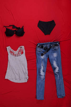 A vertical shot of various clothing items on a red surface