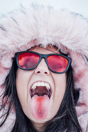 A closeup shot of a happy woman wearing a hoodie showing her tongue with a reddish streakの写真素材