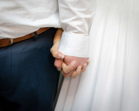 A closeup shot of the bride and the groom holding the hands of each otherの写真素材