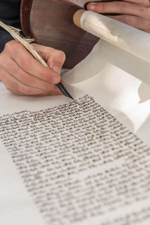 A vertical shot of a person writing with a feather on a scrollの写真素材