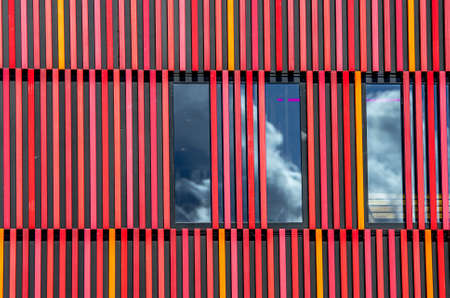 A closeup shot of a building with tall windows and a unique striped design