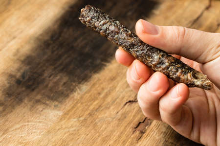 A closeup high angle shot of a person holding a piece of wood over a wooden surfaceの写真素材