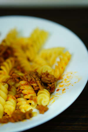 A vertical high angle closeup shot of pasta with meat in a white bowl