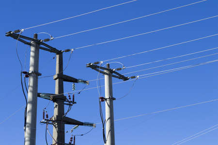 closeup shot of electric posts and lines against a blue background