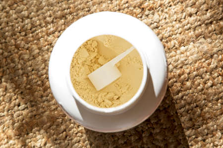 A high angle shot of a flour in a white container on a knitted carpet
