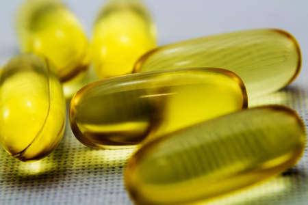 A closeup shot of some yellow transparent capsules on a white surface