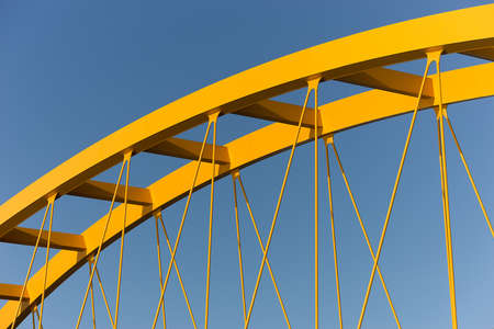 A yellow cable-stayed bridge with a clear blue sky in the background