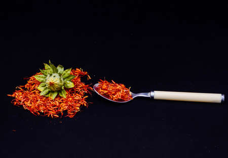 A landscape shot of green fruit with a spoon full of red petals with a pitch-black backgroundの写真素材