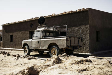 An old truck in front of a refugee camp house