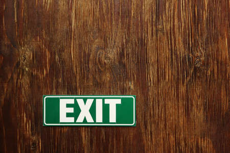 A closeup shot of a green Exit sign on a wooden surfaceの写真素材