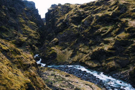 A high angle shot of a small stream surrounded by huge mossy rocks