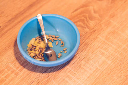 A high angle shot of different nuts and seeds in a blue bowl on a wooden surfaceの写真素材