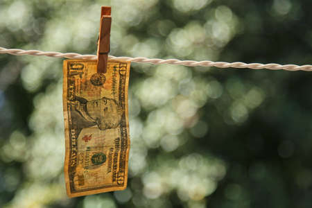 A selective focus shot of a banknote hung from a wire with a clothespinの写真素材