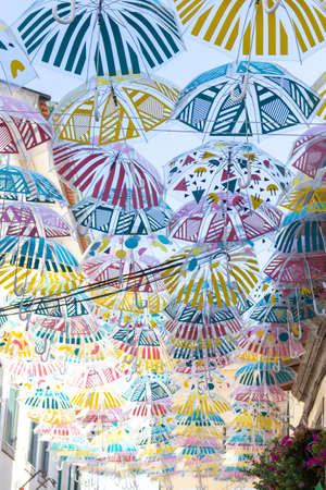 A vertical shot of a beautiful display of colorful hanging umbrellas with geometric designの写真素材