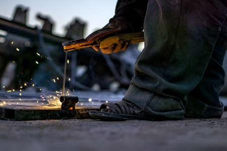 A factory worker with working clothes welding in a factory with a blurred background