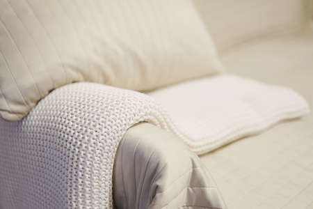 A white cozy blanket on a sofa with a blurred background