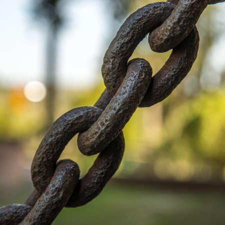 A closeup shot of a big dark iron chain with a blurred backgroundの写真素材