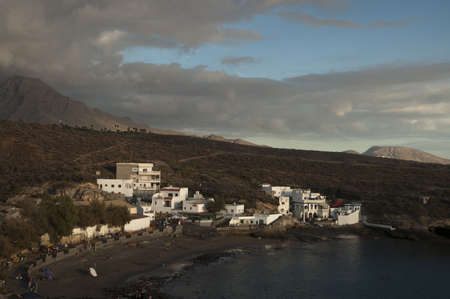 A high angle view of hills covered with houses and greenery surrounded by the sea under a cloudy sky