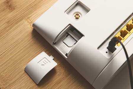 A closeup shot of an internet router with its back open on a wooden surface