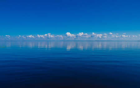 A landscape of the sea under a blue sky with the clouds reflecting on the water