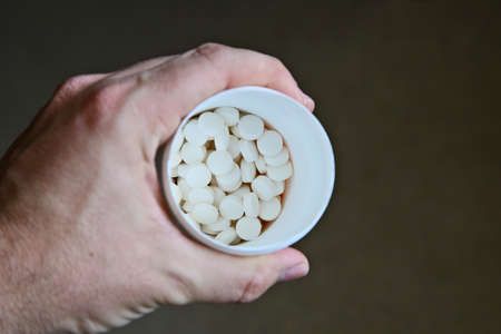 A high angle shot of a person holding a bottle of white pills