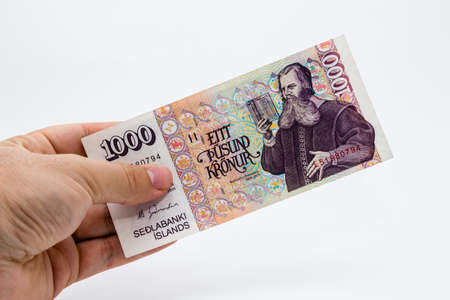 A high angle closeup shot of a person holding a banknote over a white background