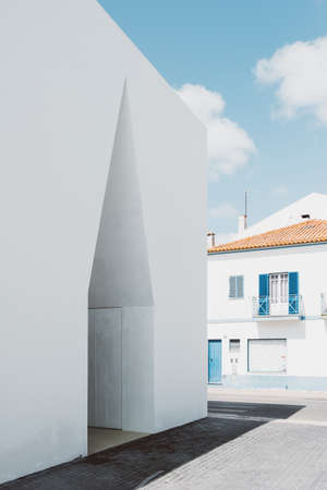 A closeup shot of a white concrete building near a houseの写真素材