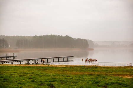SWIECIE, POLAND - Dec 25, 2019: Deczno natural lake with bathing group of people on a cold day in...