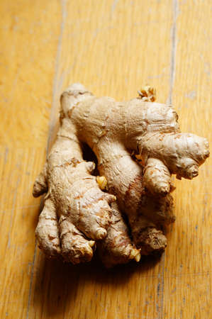 A vertical high angle closeup shot of raw ginger on a wooden surface