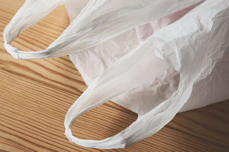 A selective focus shot of a white grocery bag on a wooden surface