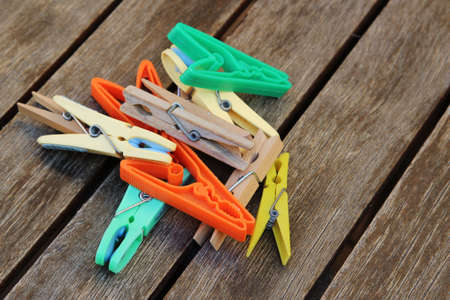 A high angle shot of colorful wooden and plastic clothespins on a wooden surface