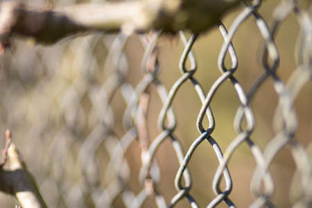A closeup shot of a gray chain-link fence with a blurred background