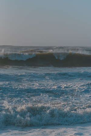 A vertical shot of sea waves under a cloudy skyの写真素材