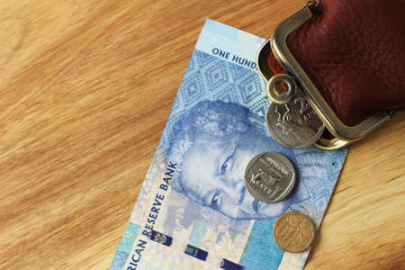 A high angle shot of a leather change purse and some change and a banknote on a wooden surfaceの写真素材
